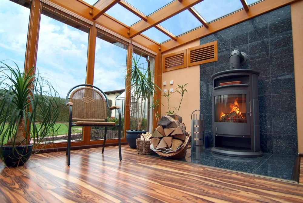 Wintergarten mit Kamin hinter großen Glasflächen